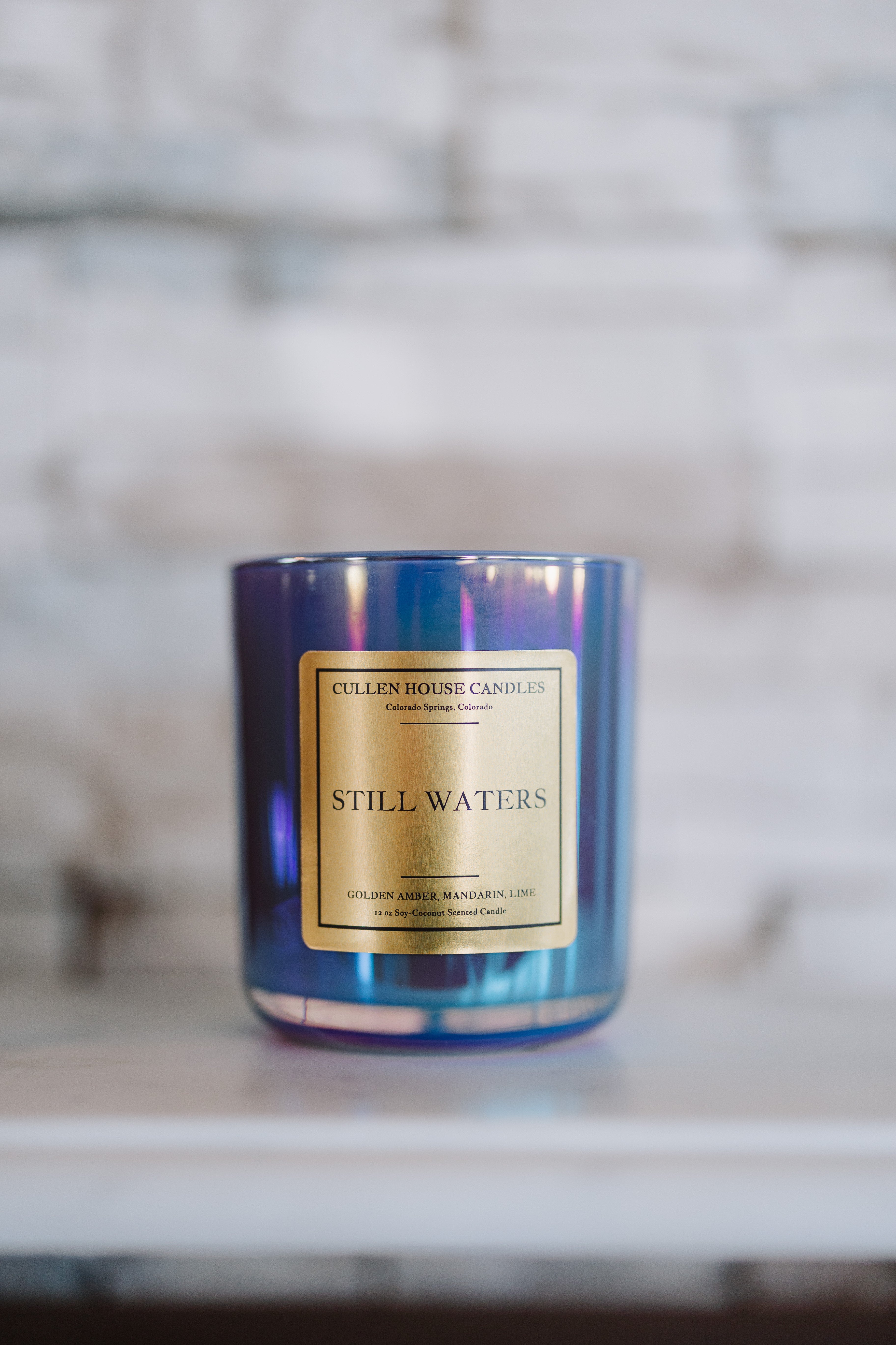 Candle with a blue tinge and gold label on a blurred background